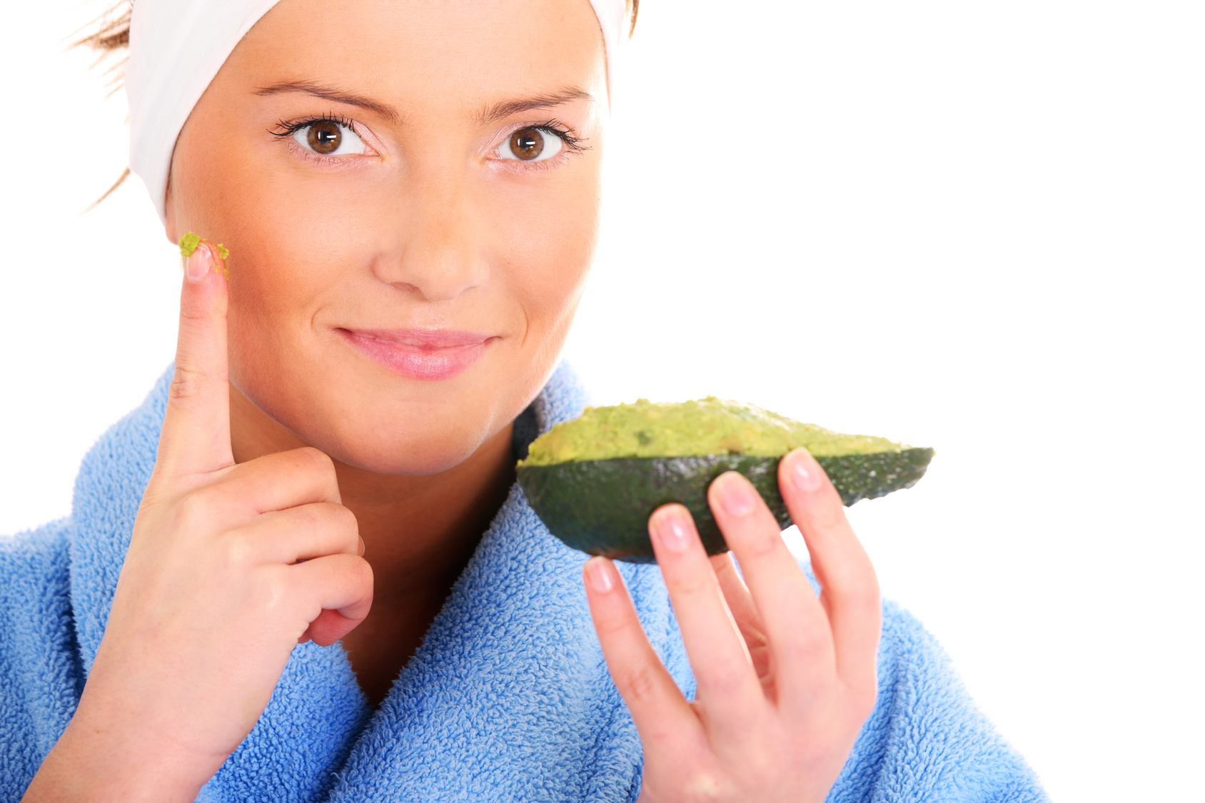 A portrait of a young woman applying natural avocado mask on her face